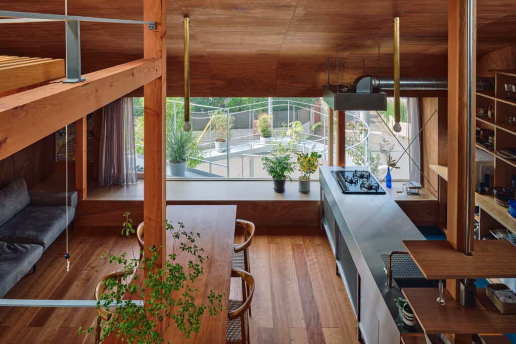 View from a modern kitchen through a large north-facing window looking out onto a curved terrace with plants.