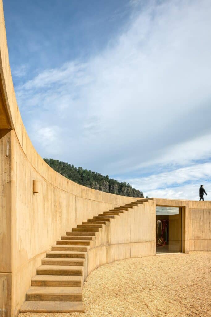 Concrete stairs integrated into the curved exterior wall leading to the rooftop terrace.