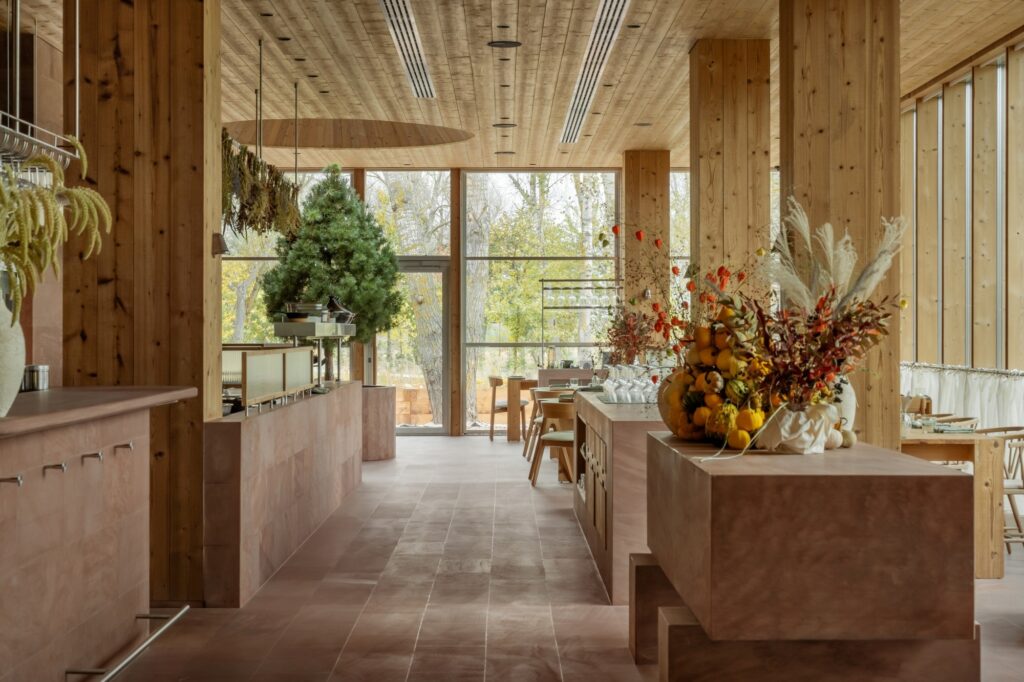 Interior corridor of Seven Lakes restaurant with stone-clad walls, wooden pillars, and decorative autumn harvest arrangements.