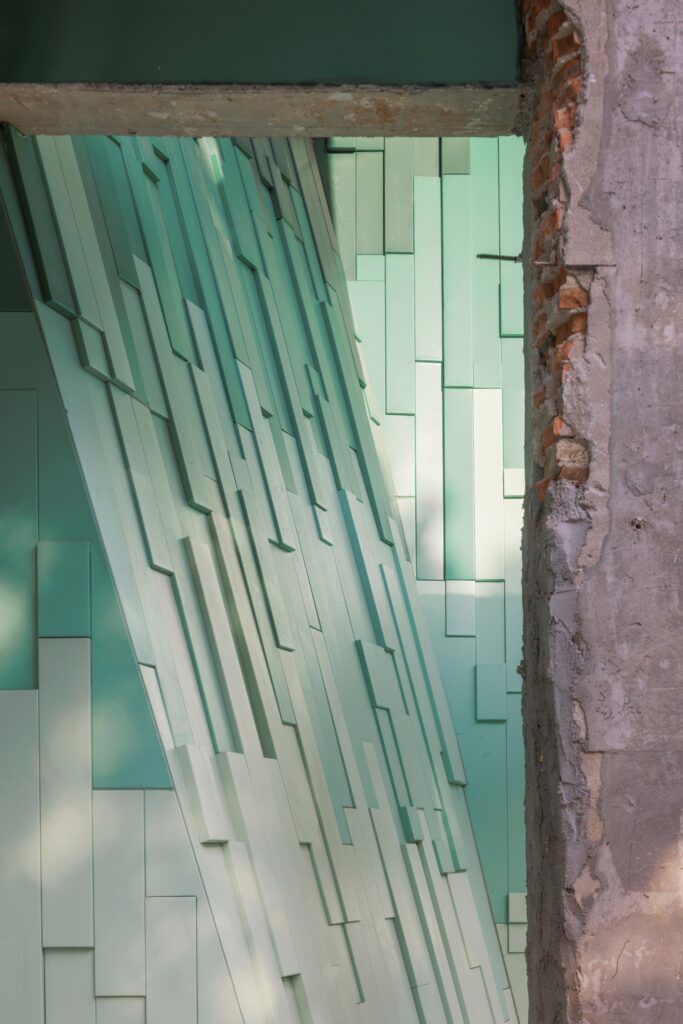 Perspective view through concrete openings showing the layered, ethereal mountain shadows created by the metal mesh.