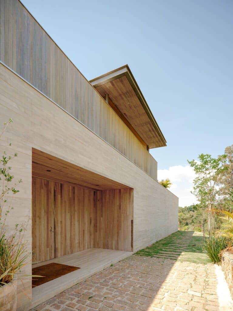 Close-up of the concrete wall and wooden entrance niche with a stone-paved pathway at Casa CR JL.
