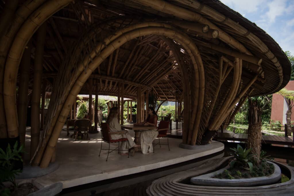 Guests sitting in a bamboo pavilion with views of an internal garden and curved bamboo beams.