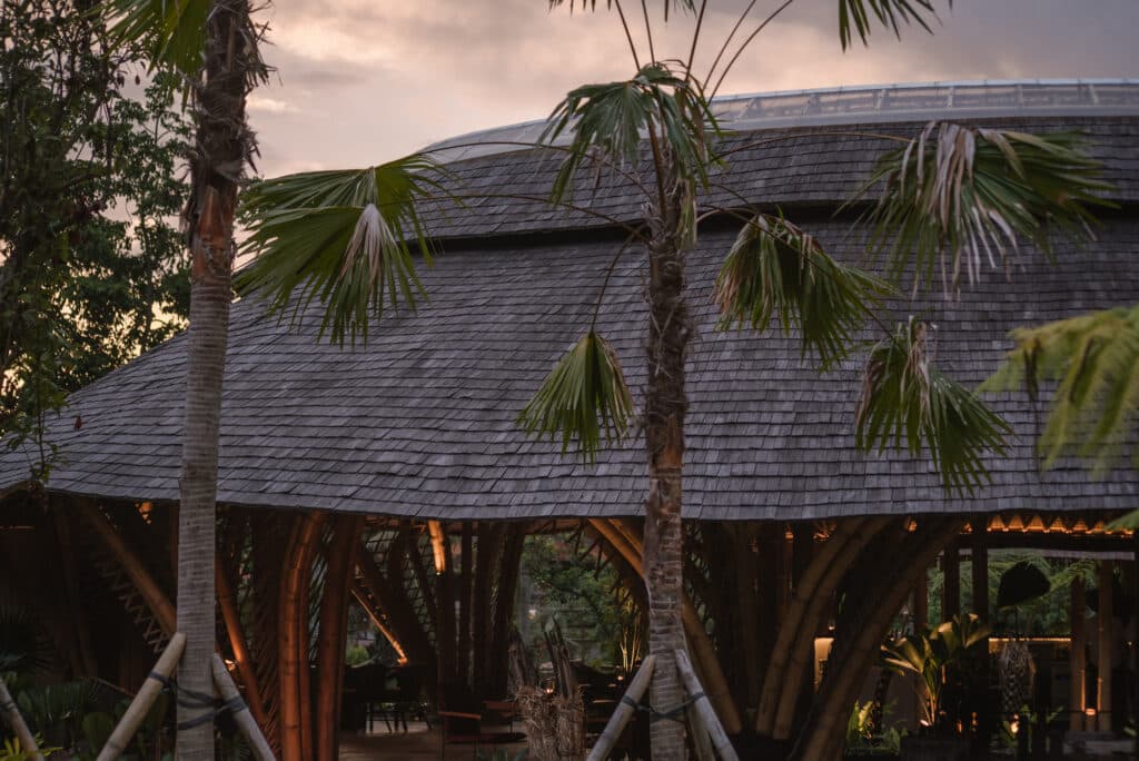 Exterior view of Juna restaurant at dusk showing the SolarTuff skylight and bamboo roof texture.
