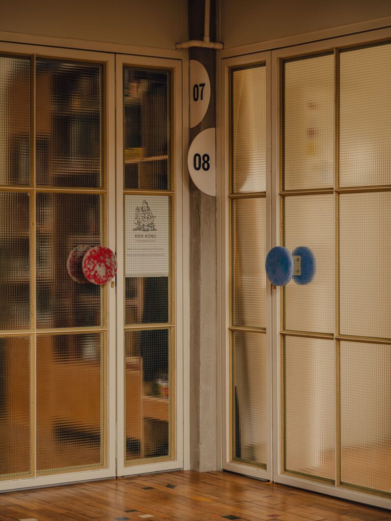 Close-up of glass studio doors in Grid Arthub with colorful recycled plastic door handles.