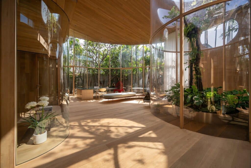 Wide-angle interior shot of Terrarium House showing the integration of curved glass walls and the central garden area.