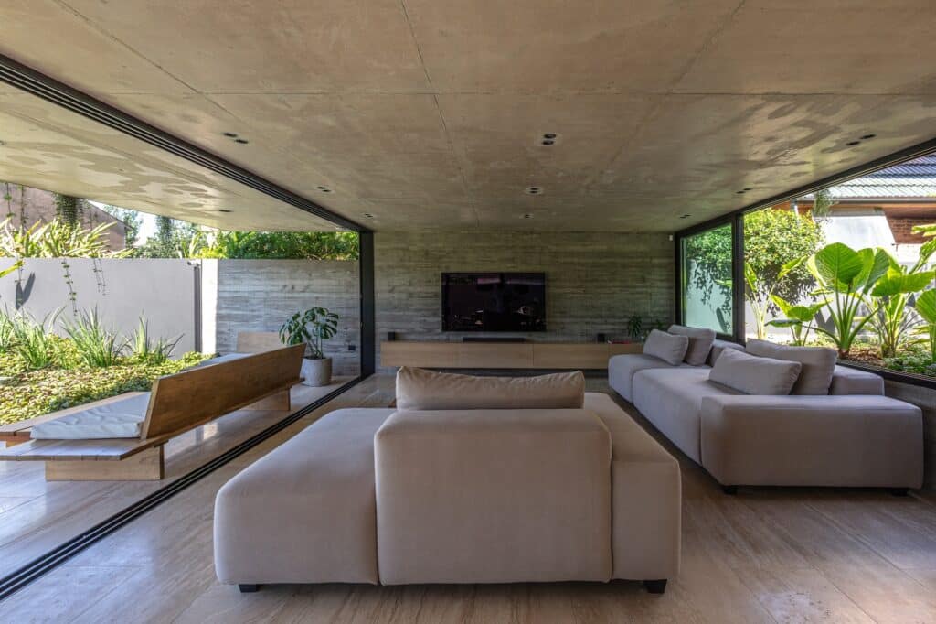 Modern living room with low-profile beige sofas, wooden furniture, and board-marked concrete walls at Casa Machado.
