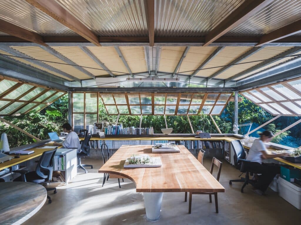 Panoramic interior of the architectural office with central model table and panoramic windows.