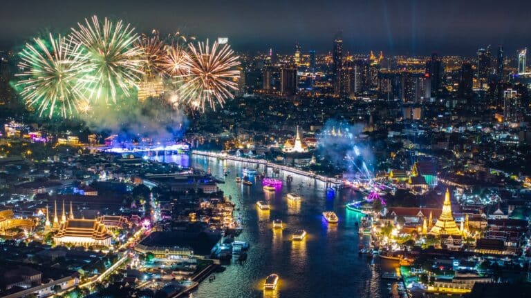 Night aerial view of Bangkok showing Chao Phraya River, bridges, temples, and fireworks Chao Phraya Pedestrian Bridge