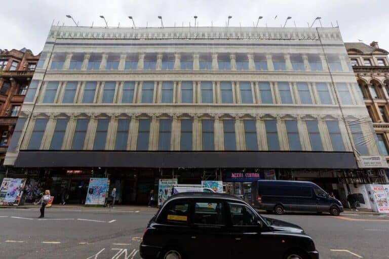 A nighttime rendering of the revived Egyptian Halls in Glasgow, showcasing its illuminated historic facade and a new rooftop pavilion.