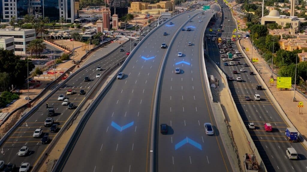 An aerial view of the new Al Qudra Road Bridge, showing traffic flowing smoothly over the multi-lane overpass in a desert landscape.