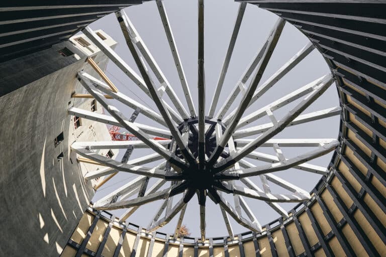 A multi-story residential building featuring a prominent timber frame and colorful recessed balconies, showcasing modern Timber Construction.