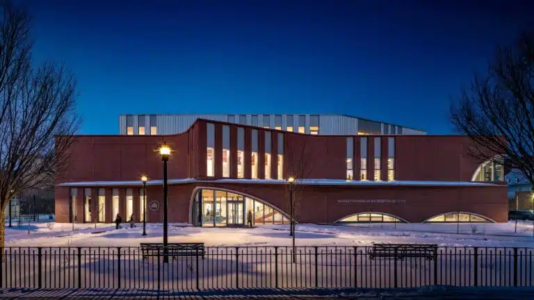 The striking curved brick facade of the new Brooklyn Community Recreation Center, with large arched windows reflecting the daylight.