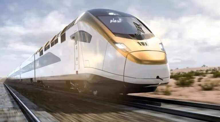 A sleek, white High-Speed Railway train at a modern, brightly-lit station platform. The station features a curved, white architectural canopy, with passengers waiting, providing a sense of scale.