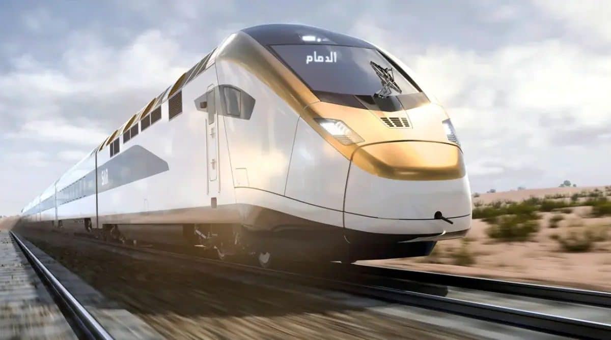 A sleek, white High-Speed Railway train at a modern, brightly-lit station platform. The station features a curved, white architectural canopy, with passengers waiting, providing a sense of scale.