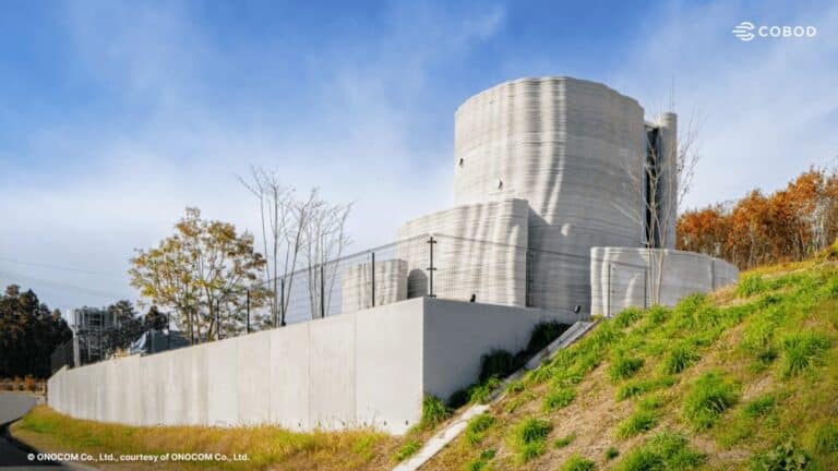 Exterior view of Japan's first two-storey 3D-printed house in Miyagi Prefecture, featuring curved reinforced concrete walls and seismic-resistant design.
