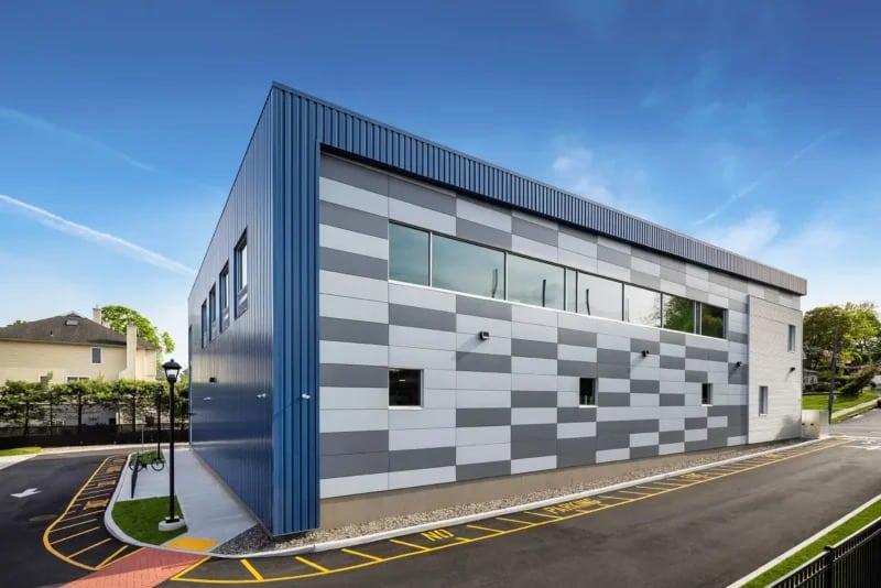 Exterior of Remington Clubhouse featuring flood-resilient architecture with elevated foundation and blue corrugated metal panels.