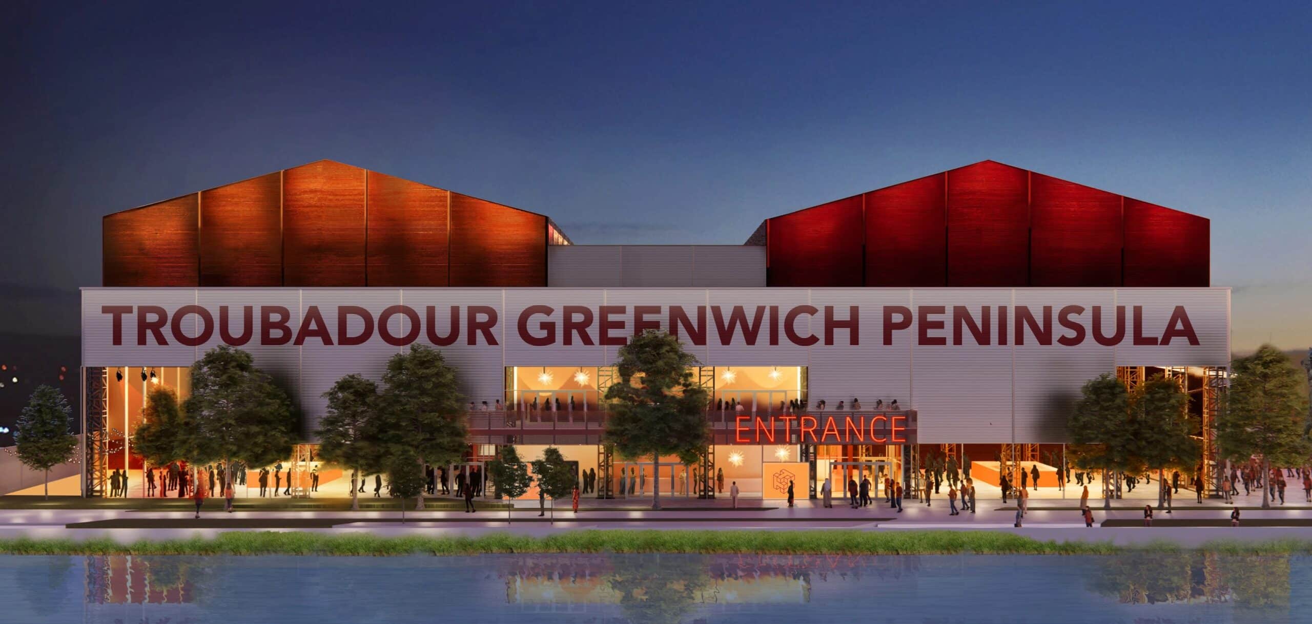 A wide exterior view of the large, modern Troubadour Greenwich Peninsula Theatre, showing its main entrance and facade against a clear sky.
