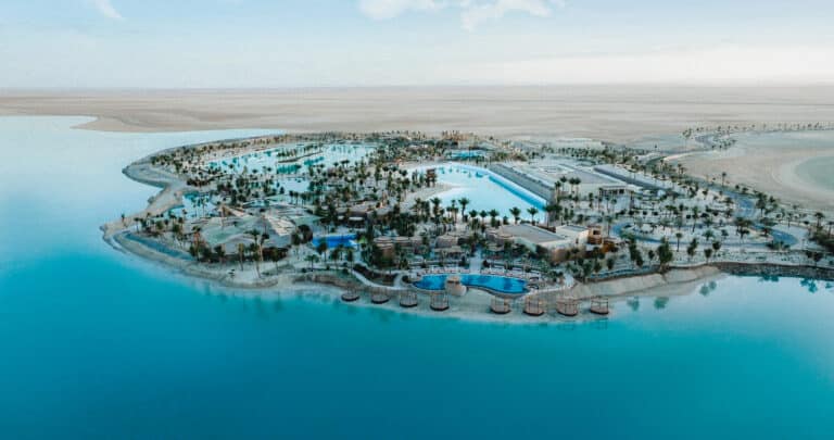 Aerial view of the massive 215-meter Saltwater surf pool at ADRENA district surrounded by desert landscape and Red Sea coast.