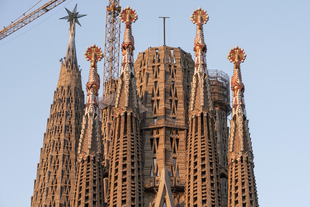Close-up view of the intricate stone pinnacles, colorful ceramic details, and "Hosanna" inscriptions on the Sagrada Familia tower spires.