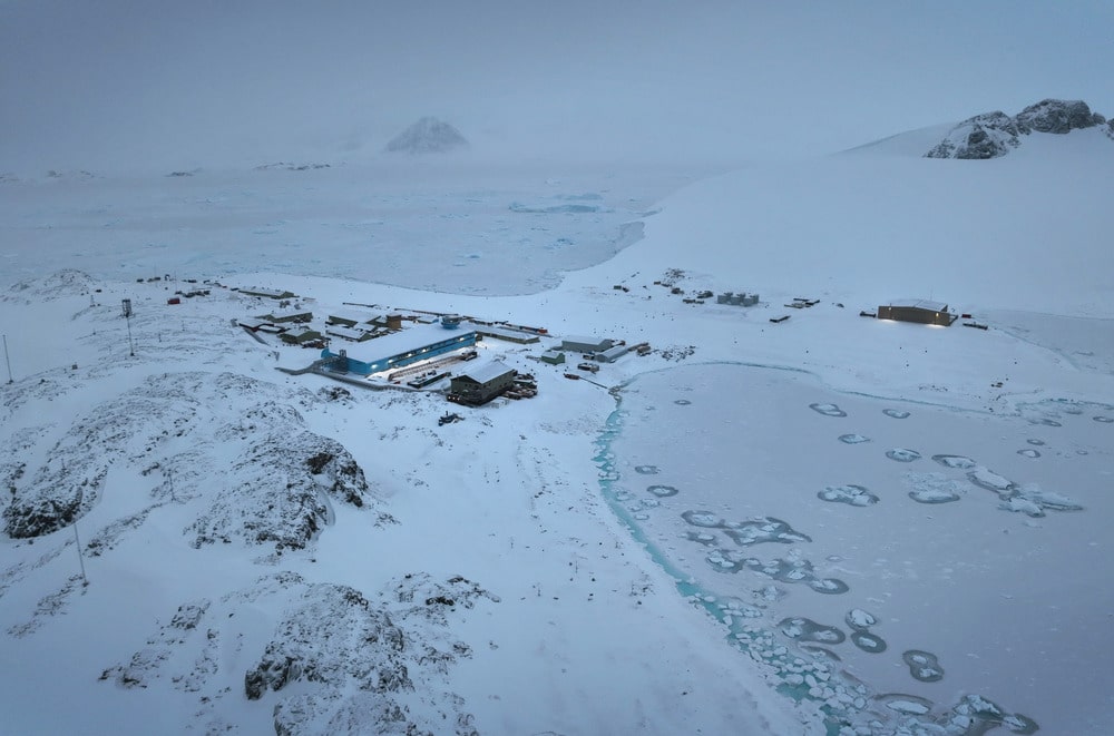 Illuminated Discovery Building at Rothera Research Station surrounded by snow and sea ice, illustrating the challenges of modern Antarctica construction.