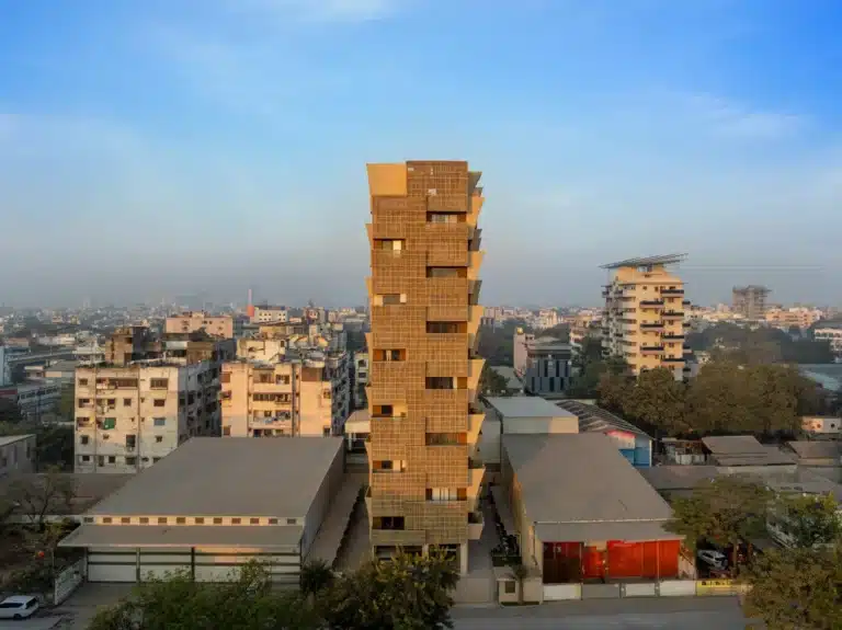 Full exterior view of the 12-storey Cielo Tower rising above the Nagpur skyline, featuring a pixelated beige facade against a blue sky.