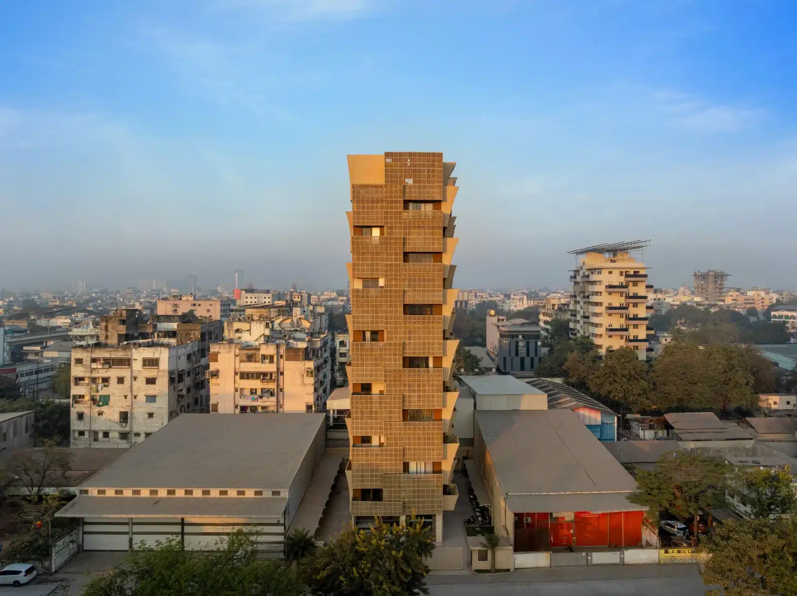 Full exterior view of the 12-storey Cielo Tower rising above the Nagpur skyline, featuring a pixelated beige facade against a blue sky.
