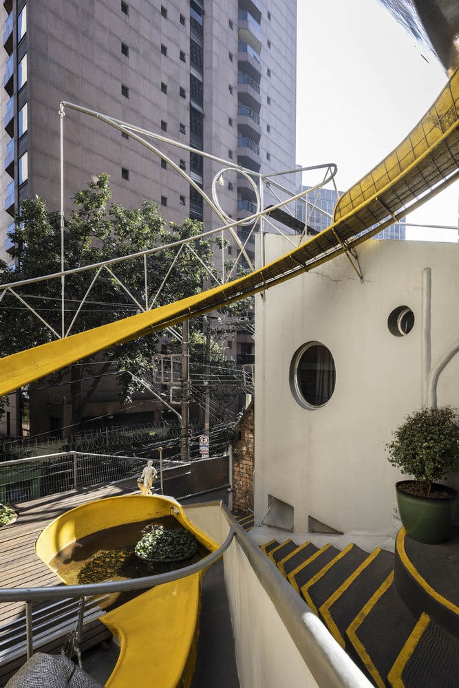 Rooftop terrace of the Spherical House featuring a yellow slide, circular windows, and organic architectural forms.