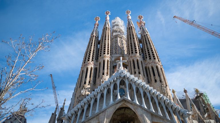 Low angle vertical view of the Passion Facade columns and scaffolding surrounding the central Sagrada Familia tower structure during construction.