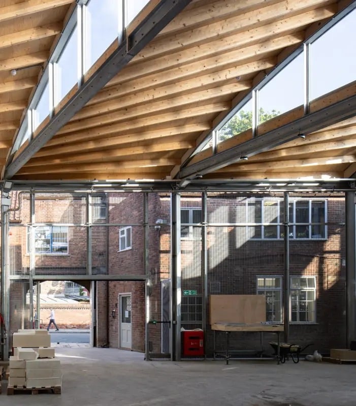 Interior view of the Technology Hub at York Minster, showing a modern workshop space where a CNC machine works on a large block of stone, blending advanced technology with traditional craft.
