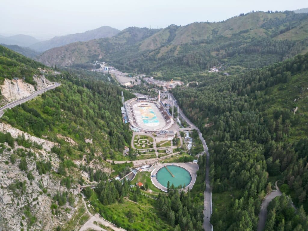 Aerial view of the Medeu outdoor skating rink and the mudflow control dam nestled in a valley, highlighting engineering within the landscape.