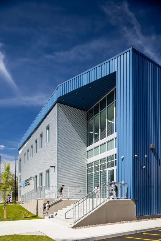 Main entrance of the youth center showcasing flood-resilient architecture design with double-height glazing.