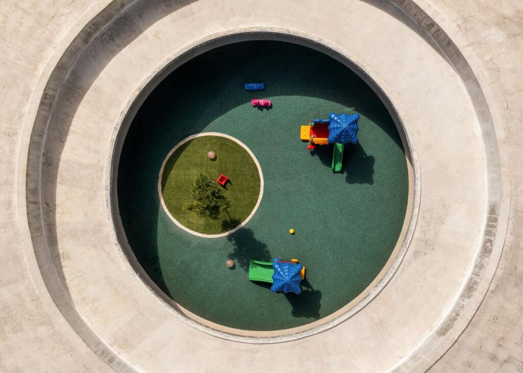 Top-down aerial drone shot showing the geometric concrete ring and central green oculus of the facility.