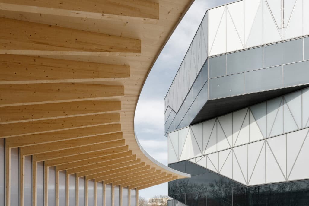 The vibrant, colorful facade of the Berlin Metropolitan School extension, featuring vertical timber elements and large windows, showcasing excellent Timber Construction.