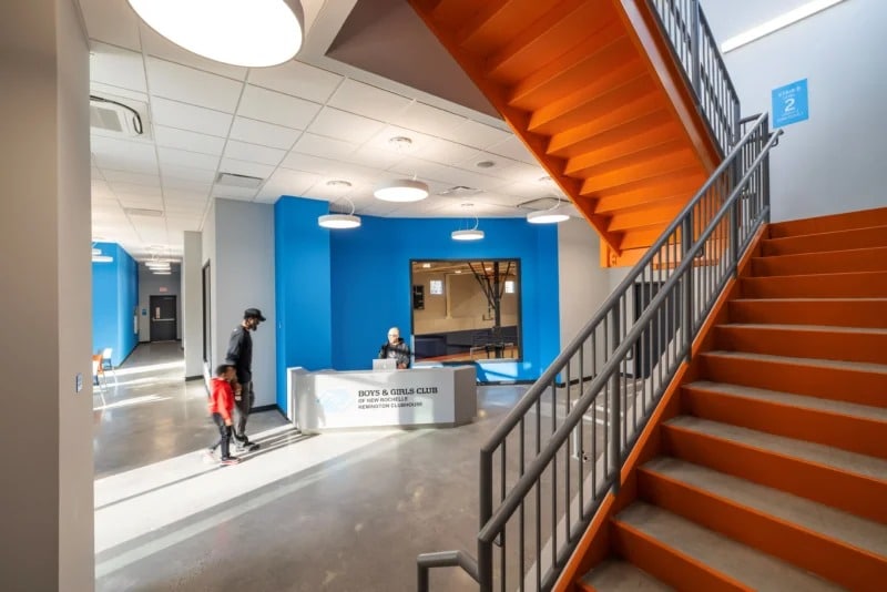Bright orange steel staircase in the lobby of the Remington Clubhouse connecting youth activity spaces.