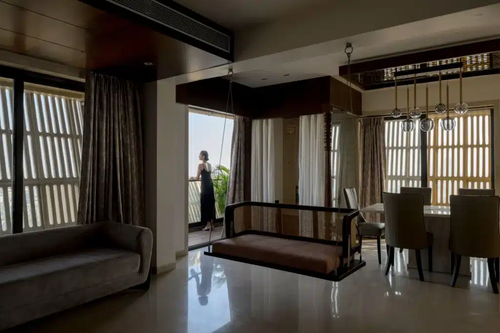 Luxury interior living room with a traditional wooden swing and marble flooring, opening onto a balcony screened by the perforated facade.