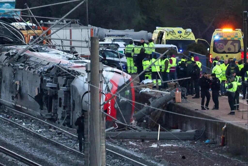 Overturned red Iryo train and sheared concrete catenary poles at the center of the Spain Train Disaster site.