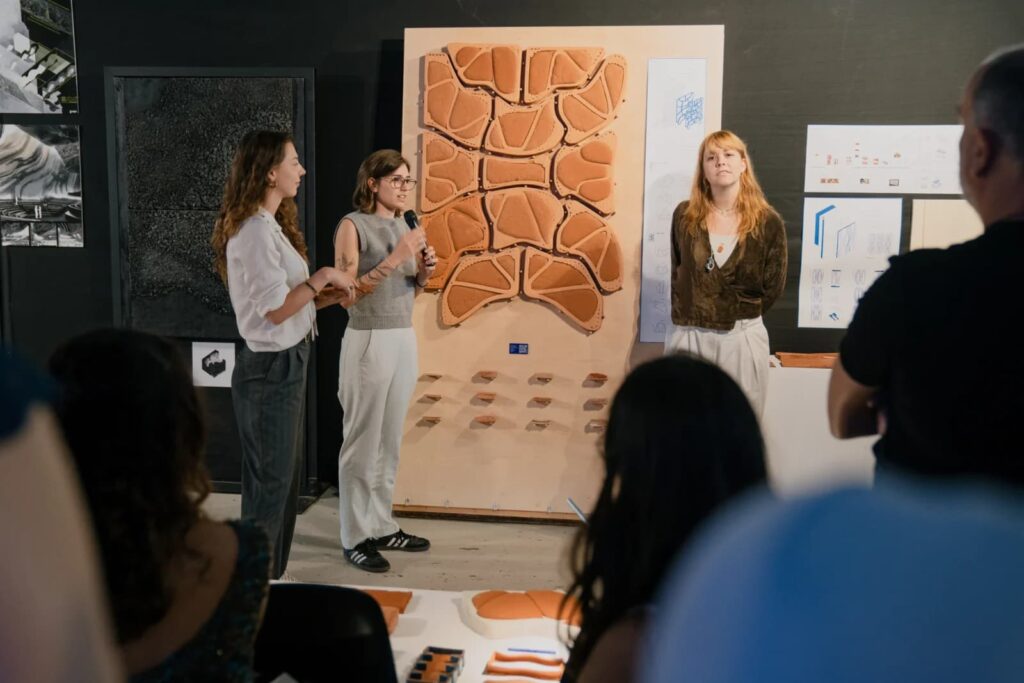 ذراع روبوتية تقوم بالطباعة ثلاثية الأبعاد لهيكل طيني، مما يوضح التكنولوجيا المتقدمة المستخدمة في برامج التعليم المعماري في IAAC.