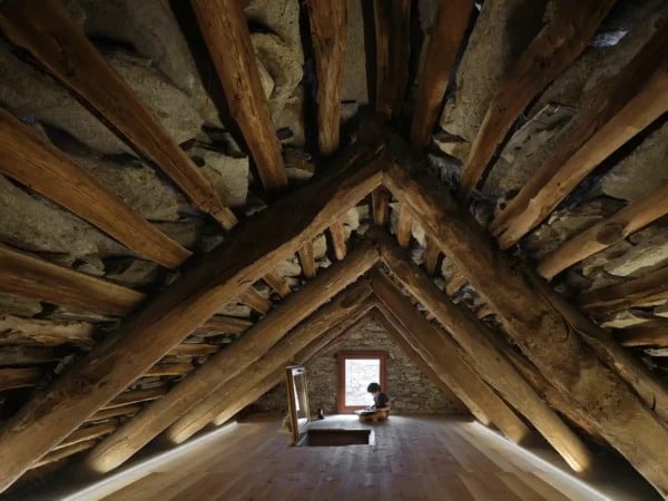 A compact, modern bathroom with bold red flooring, a floating wooden vanity, and a stone vessel sink under a small window.