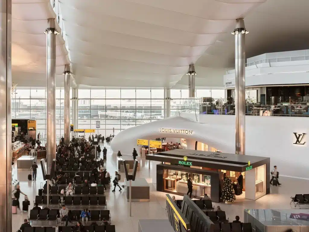 Wide shot of the white Fuselage Architecture pavilion located within the busy environment of Heathrow Terminal 2.