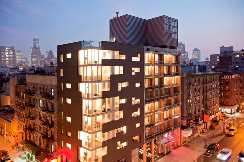 تصوير معماري ليلي لبرج أبارتهوتل ستراتفورد مضاءً أمام أفق شرق لندن.