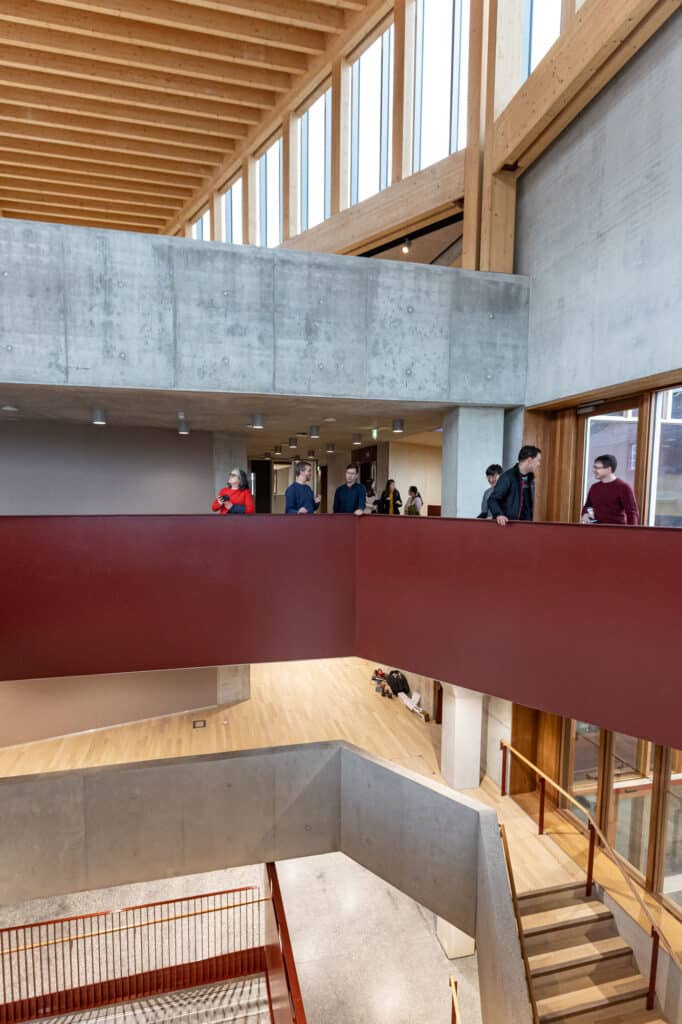 Detail shot of the interior staircase highlighting the contrast between exposed concrete and warm timber materials.