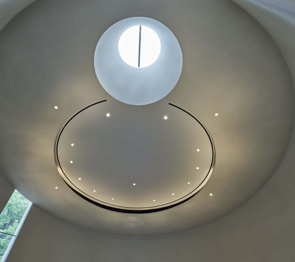 Interior view looking up at the central circular skylight and curved ceiling geometry in the sacred space.