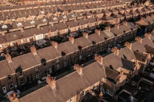 High-angle aerial view of long rows of red-brick terraced houses with slate roofs and chimney pots under warm evening sunlight.