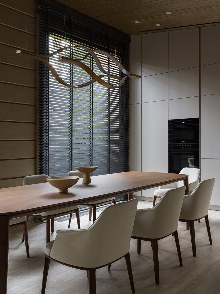 Open-plan living, dining, and kitchen interior featuring Flexform Groundpiece sofa, Poliform Henry table, Henge Tape chandelier, and Leicht kitchen