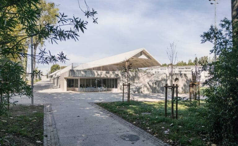 Main entrance of the Ramalde Sports Park support building featuring a concrete staircase and integrated greenery.