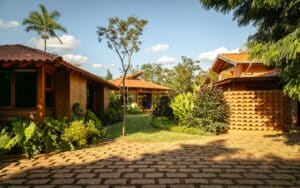 Modern residential expansion featuring wooden structures and traditional clay tile roofs integrated with lush green landscaping and stone pathways.