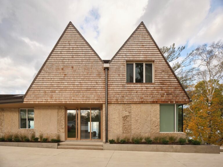 Front facade of a modern Georgian Bay house featuring symmetrical twin gables, cedar shingle roofing, and local limestone walls.