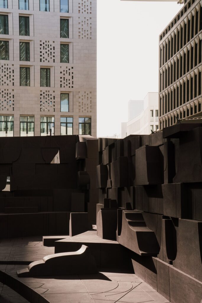 Vertical close-up of the textured wall of the Counterspace installation against the backdrop of modern stone buildings in Msheireb Downtown Doha.