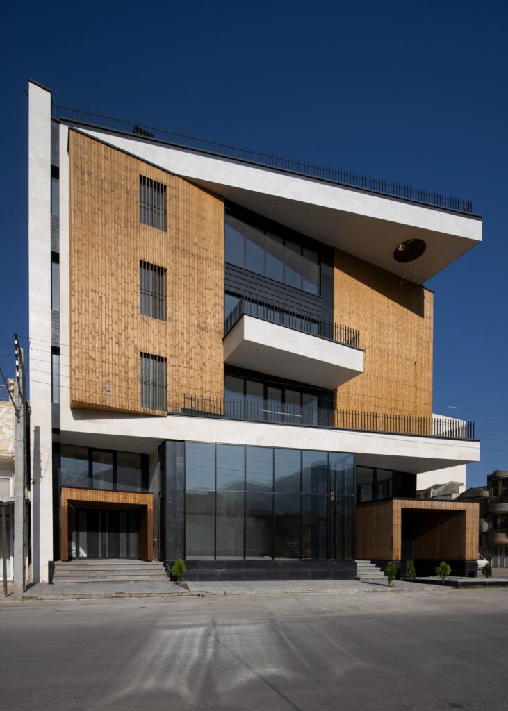 Low-angle shot of the Ramand Ho building showcasing the cantilevered wooden cube and glass ground floor.