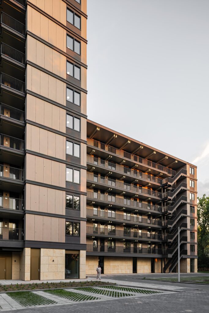 Low-angle view of the Valckensteyn building featuring the external steel staircase and the contrast between wood panels and stone cladding.